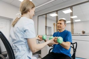 Occupational therapist assisting senior man with green dumbbells in rehabilitation session, highlighting effective therapy services in Australia.